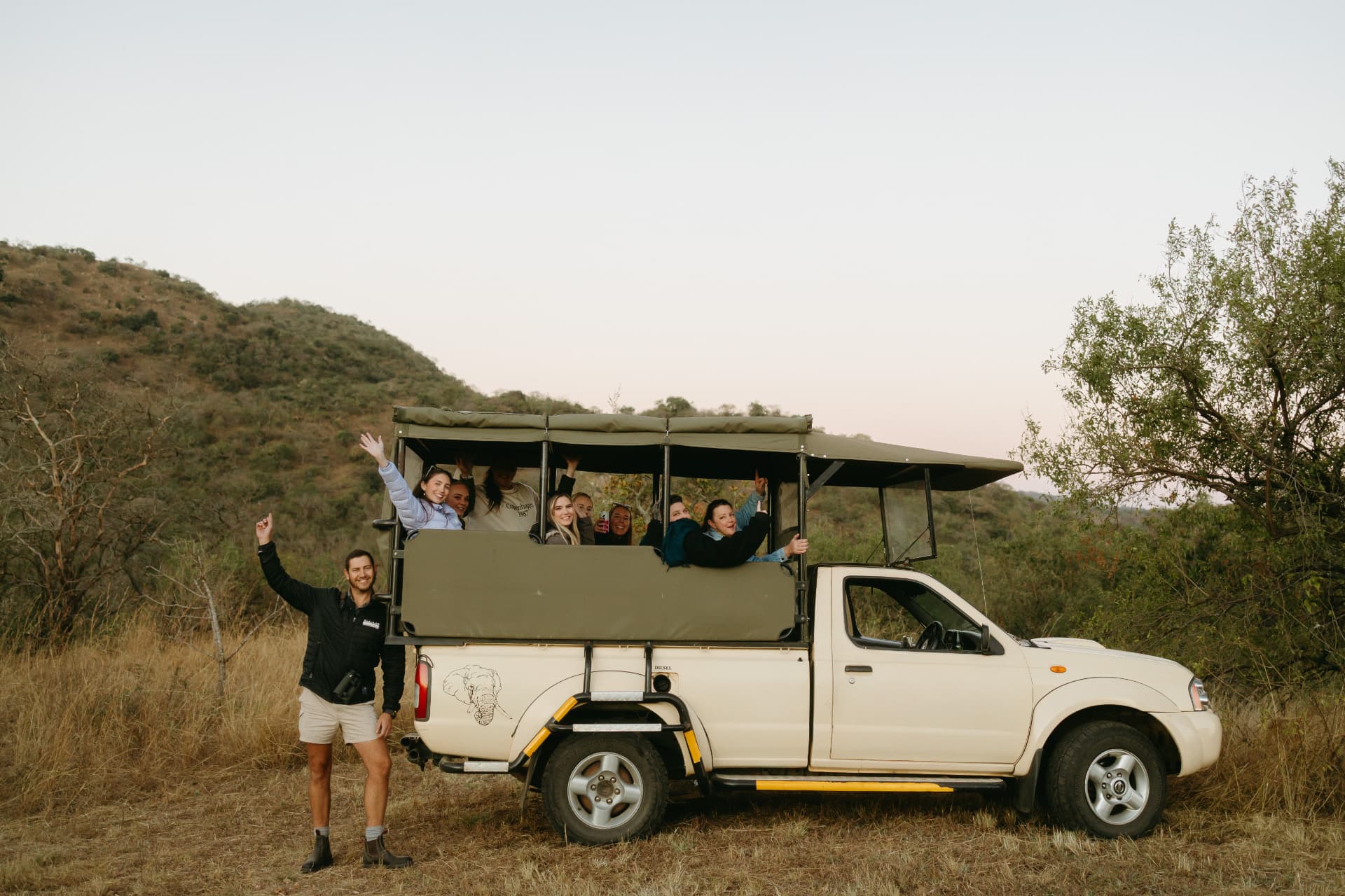 Guests waving from an open game viewer at sunset