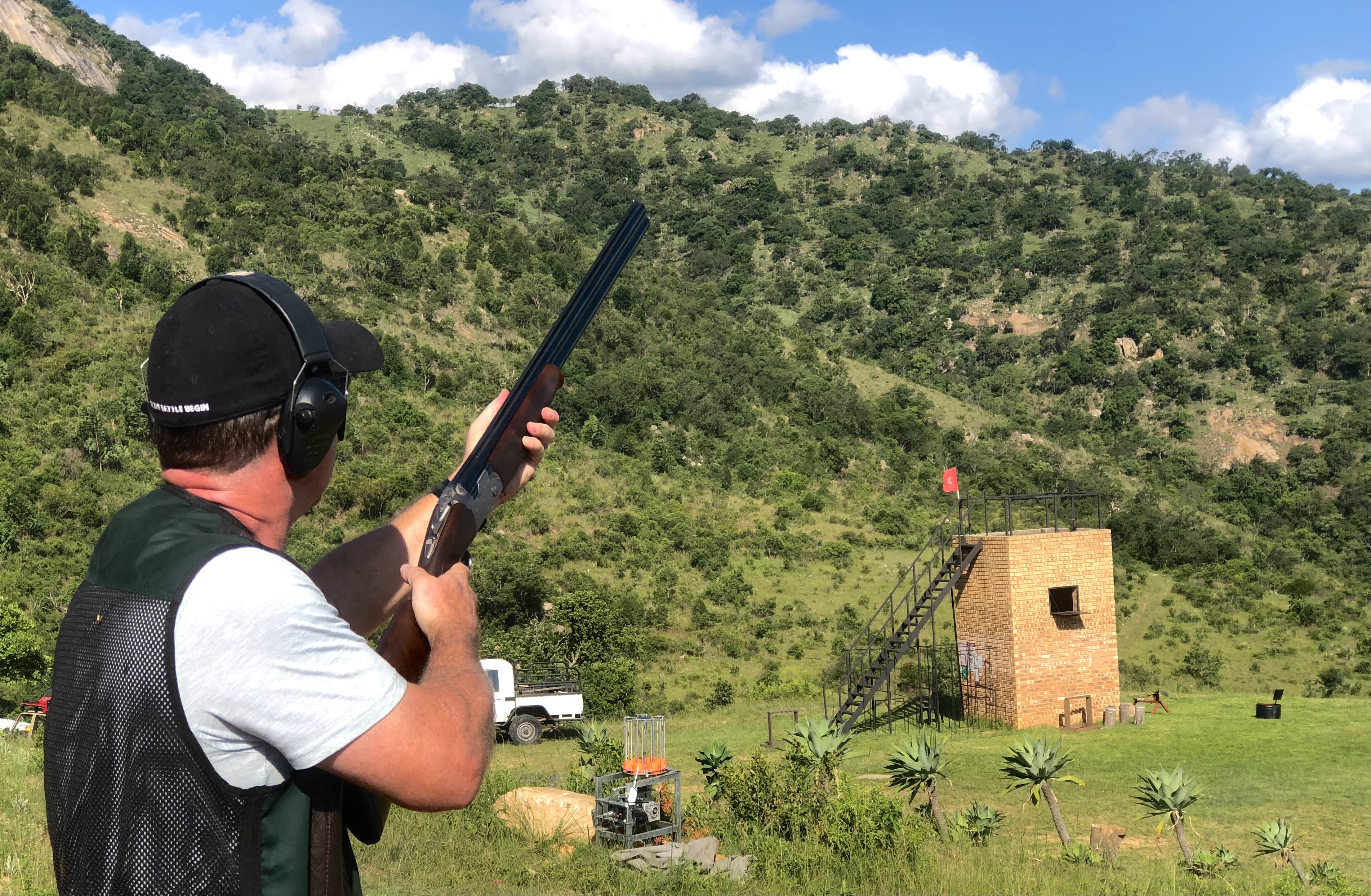 Shooter calling for a target beside the trap house with the hills behind