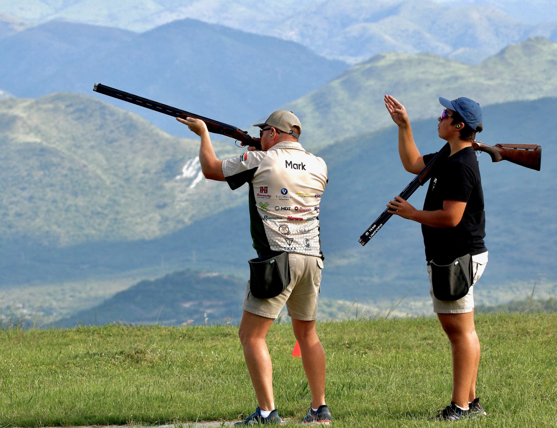 Coach guiding a junior shooter with the mountains behind