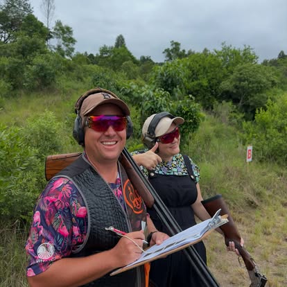 Two shooters and a scorer at a Gold Valley stand, tracking scores between rounds