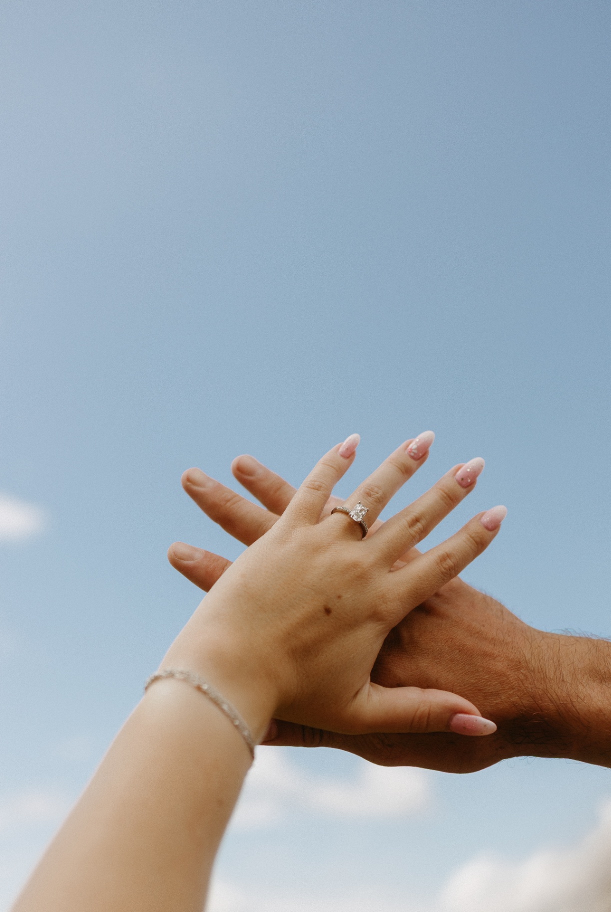 Engagement ring detail against a blue sky