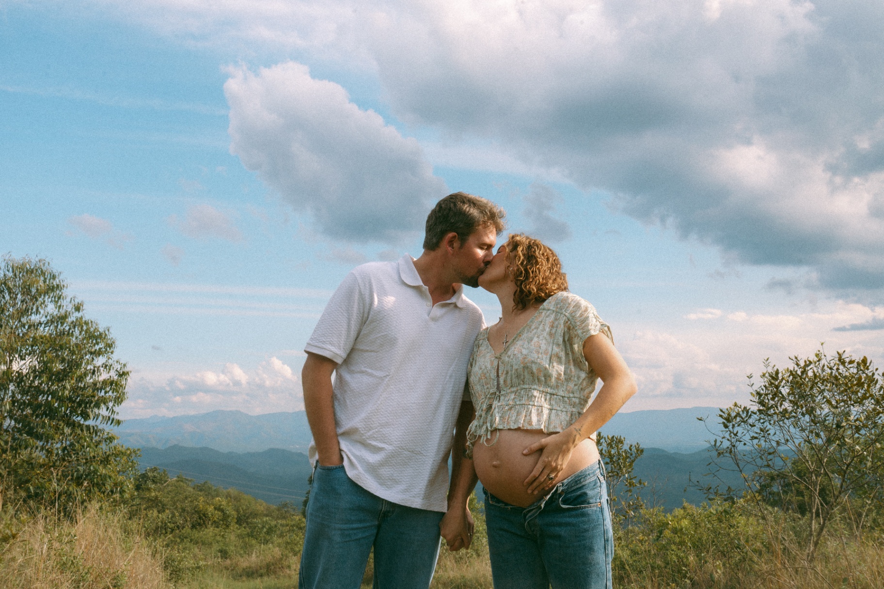 Couple embracing on a ridge with the valley beyond
